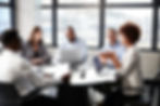 Diverse business team engaged in a discussion around a conference table.