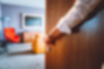 Person opening a door to a modern, brightly lit room with colorful furniture