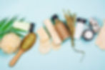 Assortment of eco-friendly personal care items, including brushes, bottles, and loofahs, displayed on a pastel background.