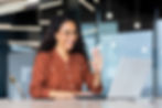 Young woman happily greeting someone via a video call in a modern office.