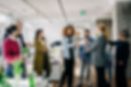 Diverse group of professionals celebrating with drinks in a bright office setting.