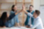 A group of coworkers celebrating success by giving each other high-fives in a cheerful office setting.