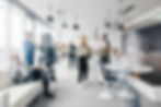 Blurred motion of people networking and working in a modern office lounge.