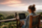 Person working on a laptop with a scenic sunset view.
