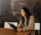 A woman smiling in a meeting room, while she works on her notepad
