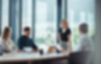 A woman leading a business meeting, smiling at her colleagues seated around a conference table.