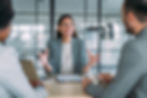 A woman in a meeting with two colleagues, smiling and providing positive feedback
