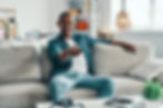 A man with a remote control, smiling while watching TV