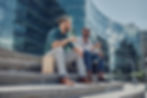 Two colleagues in business attire sitting and talking outside of the office building