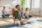 Diverse group practicing yoga together in a sunlit, spacious studio.