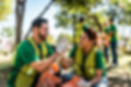 Volunteers in green vests giving high-fives while participating in a community clean-up event.