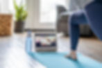 A woman practicing yoga at home, with her laptop in a call with many other yoga practitioners