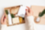 A holiday gift box containing self-care items like soap, oil, and a card reading 'Happy Holidays.