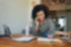 Woman smiling while taking notes during a phone call at a cozy home workspace