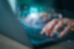Hands typing on a laptop with futuristic AI-related graphics overlay.