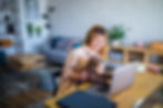 Smiling mother working on a laptop with her young child on her lap.