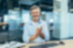 A man in the office is looking to the camera and clapping, while on a videocall