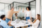 A diverse team in an office, high-fiving each other in celebration during a collaborative meeting.