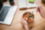A person eating a healthy meal in front of the laptop