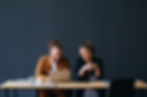 Two business professionals sitting at a table, smiling and collaborating while working on a laptop in a modern office.