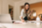 A woman working from home with her laptop, while standing and having a phonecall
