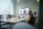 Colleagues in a meeting room, with a zoom call on a screen