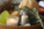 Aromatic spa essentials including oils, a candle, and fresh rosemary in a woven basket.