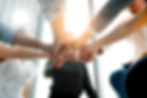 Group of professionals stacking hands in a gesture of teamwork and unity.