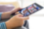 Close-up of hands selecting a movie on a tablet displaying various streaming options.