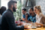 Group of friends enjoying a meal together in a bustling restaurant.