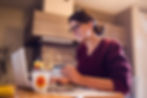 Smiling young woman working on a laptop at a cozy home office setup.
