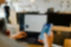 A person checking their mobile phone and laptop for new messages on their workplace collaboration app