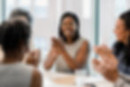 A woman applauding and smiling to her colleagues in a meeting room