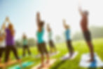 A group of people doing yoga outdoors on a sunny day