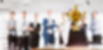 Trophy on a table with blurred businesspeople standing in the background.