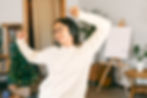 Young woman listen christmas music with headphones and dancing in living room while decorated it with christmas decoration. Funny winter holidays.