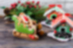 A festive display of decorated gingerbread sleigh and houses with holiday greenery and red berries.
