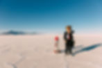 A young boy dressed in a business suit and tie stands on the Bonneville, Utah Salt Flats waiting for his new business and rocket to launch. He is wearing sunglasses and counting down to lift off while looking at his watch. The sky is blue and there is lots of copy space.