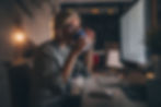 Woman working late at night, sipping from a cup while focused on her computer screen.