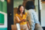 Two professional women smiling and shaking hands in a modern office environment.