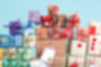 A collection of vibrant gift boxes with decorative ribbons stacked on a light blue background.