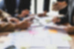 A diverse group of professionals engaged in a strategic planning session around a table filled with documents.