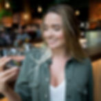 Smiling woman looking at a card in her hand while standing in a cafe.