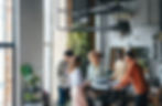 Team of colleagues having a discussion in a trendy, plant-filled office space.