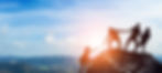 Four people helping each other climb a mountain, symbolizing teamwork and mutual support in achieving goals.