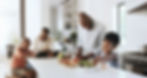 A family preparing food together in a modern kitchen, with kids helping and a cheerful atmosphere