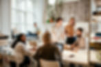A group of diverse people working in an open office, with a flexible arrangement, bright decor and plants.