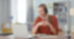 Smiling woman using a laptop with a headset in a modern home office.