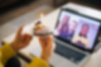 A person holding a cake with a candle in front of the camera in a zoom call with colleagues