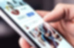 Close-up of a hand browsing a social media profile on a smartphone.
